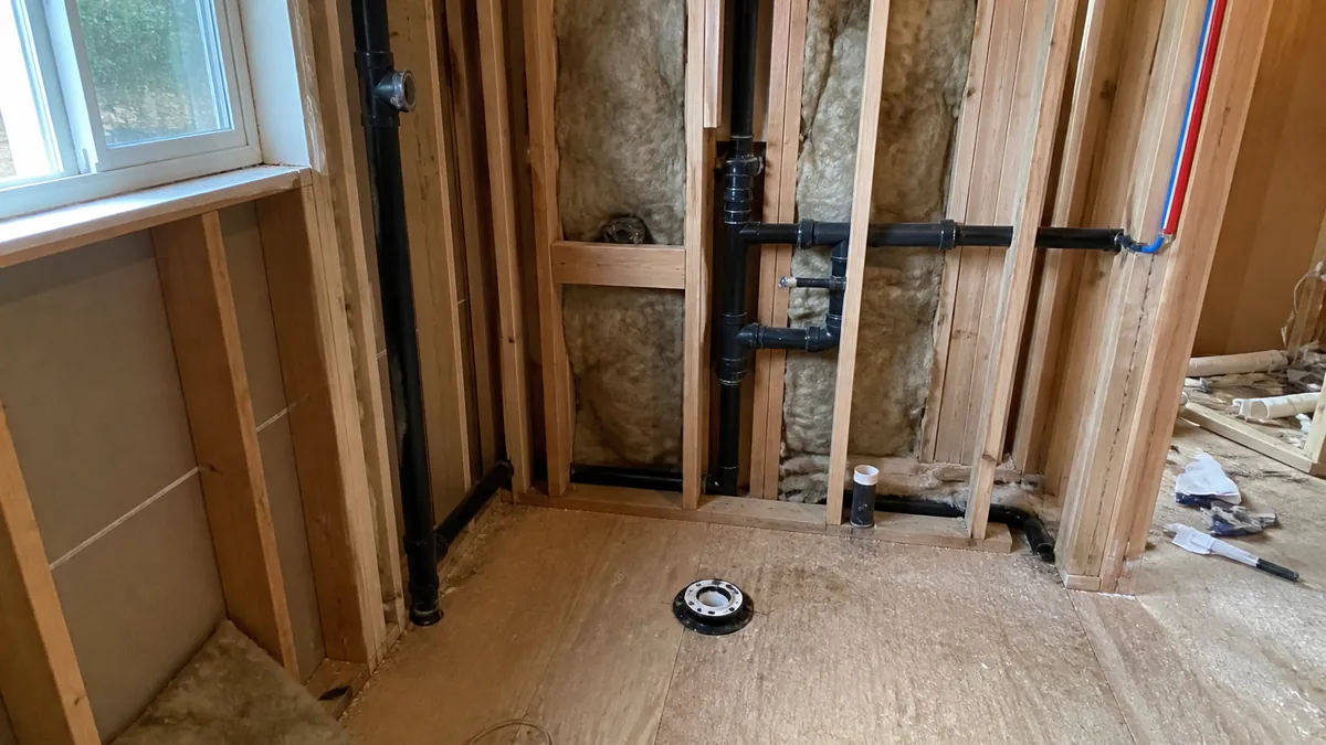 Rough-in drain and vent piping in an open stud wall on a residential job site