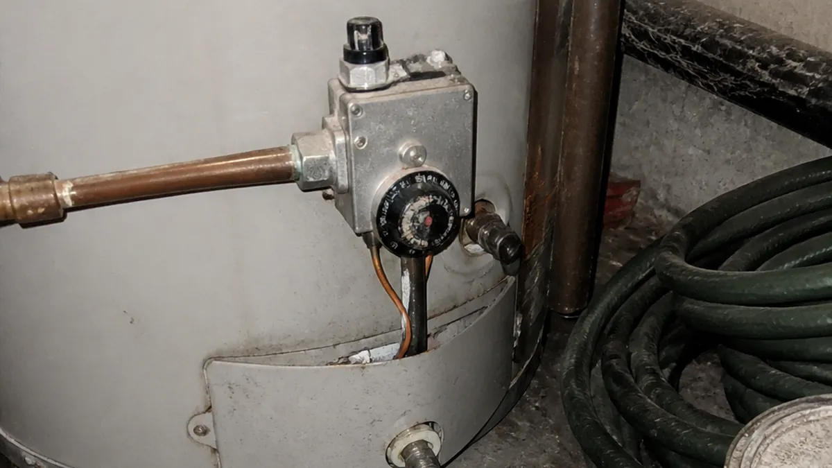 Close view of a residential water heater thermostat dial and gas control valve